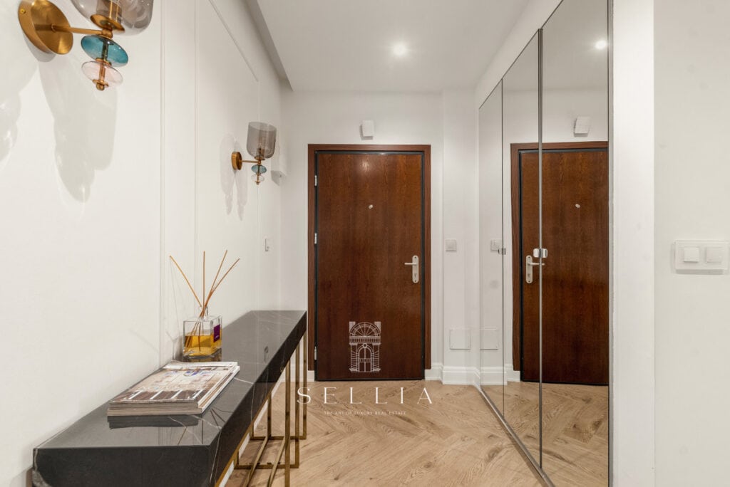 Przestronny korytarz w luksusowym penthousie z dużymi lustrami i eleganckim wykończeniem.