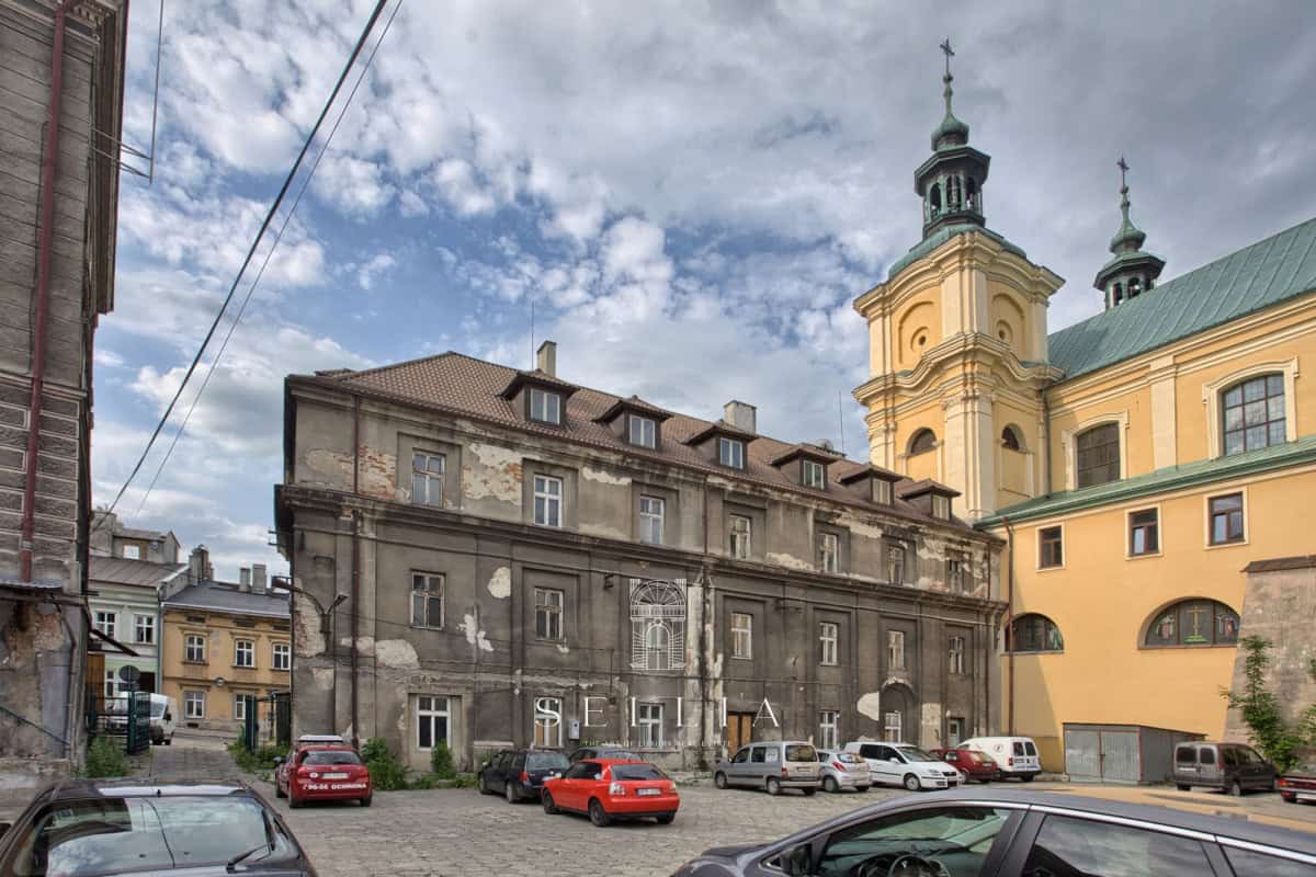 Stara kamienica w Przemyślu z parkingiem i samochodami.