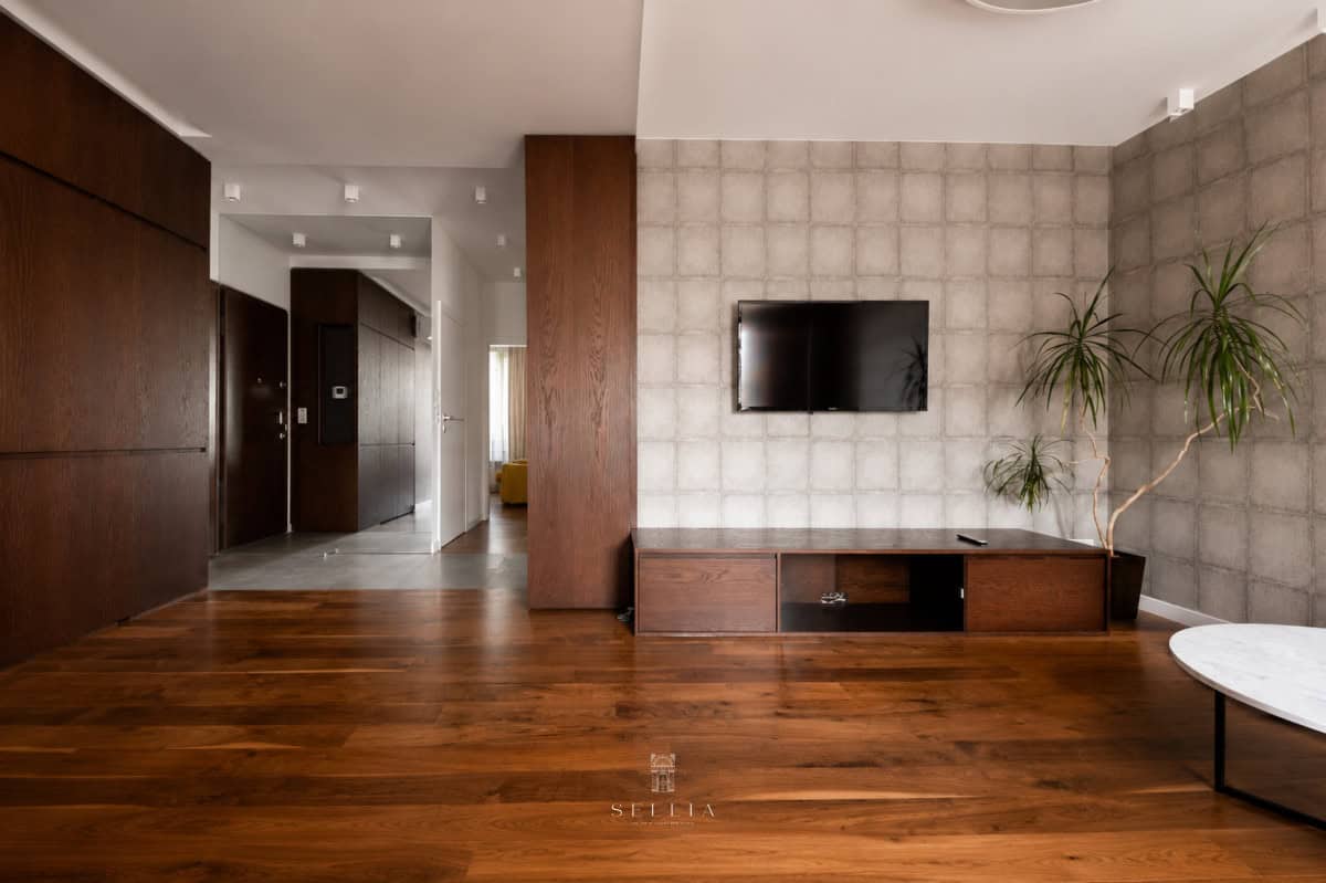 Nowoczesny salon w apartamencie na Powiślu z telewizorem i roślinami.