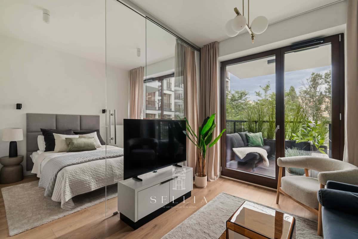 Przestronny apartament z balkonem i widokiem na zieleń, nowoczesny wystrój wnętrz.
