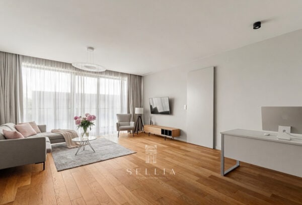 Przestronny, jasny salon z dużymi oknami i eleganckim wystrojem.