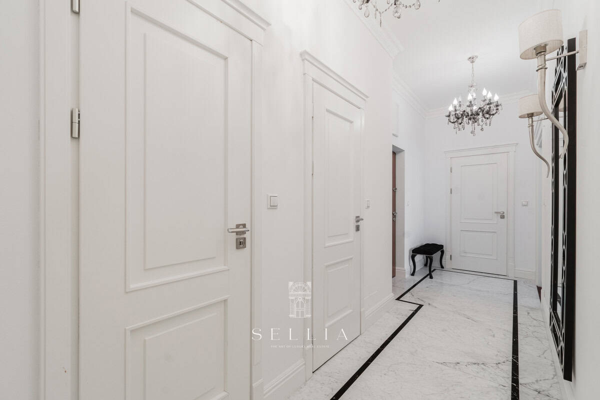 Elegancki korytarz w apartamencie z białymi drzwiami i luksusowym wykończeniem.