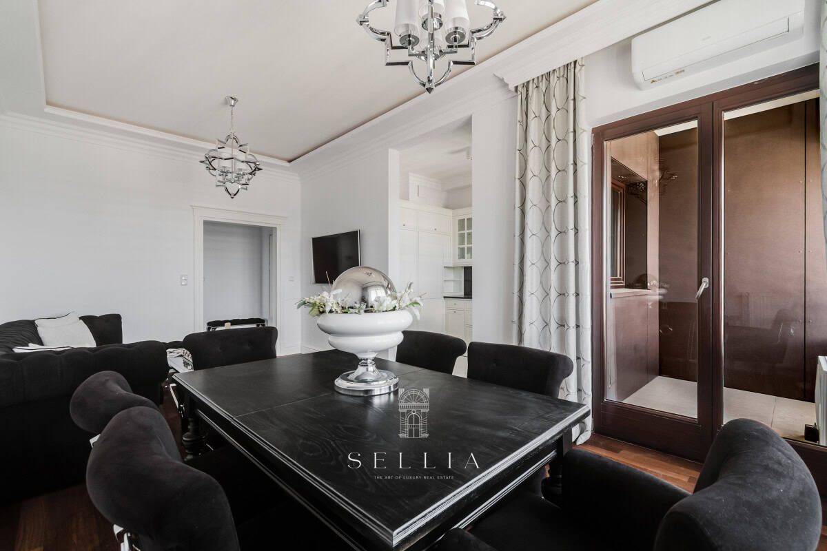 Elegancki salon z dużym stołem i tarasem w apartamencie Muranów.