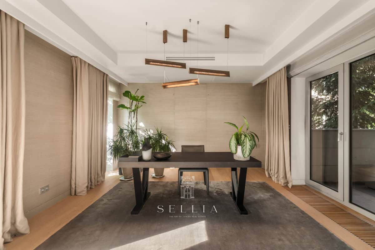 Przestronny salon z dużymi oknami i roślinami w apartamencie.